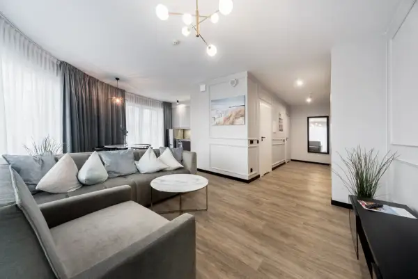 Nowoczesny apartament z szarą sofą, okrągłym stolikiem i widokiem na kuchnię.